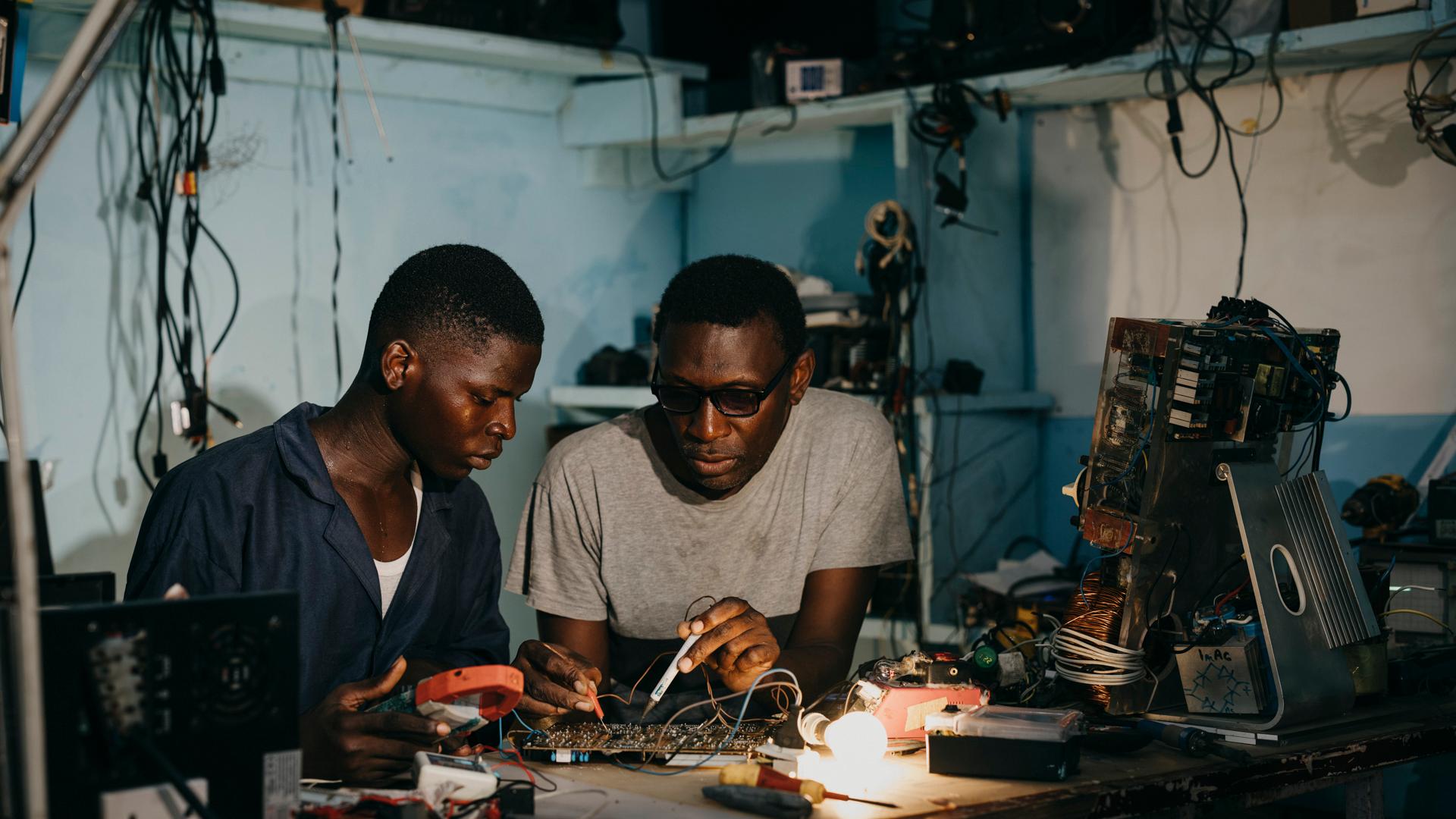 Silas (links) und Ulrich schauen zu ihrem Ausbilder Bertrand Njomko (rechts) auf, denn er ist nicht nur ein guter Lehrmeister, sondern ein Visionär. Er hat ein Konzept der Kreislaufwirtschaft für das Viertel entwickelt: „Wir verwenden hier alles nochmal, das Wenigste landet auf dem Müll.“